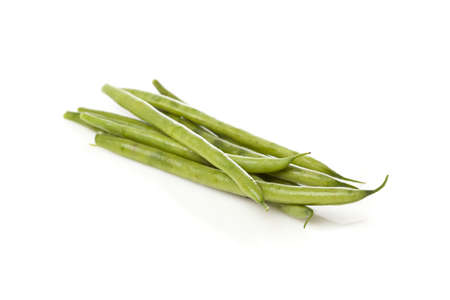 A fresh green string bean against a white background