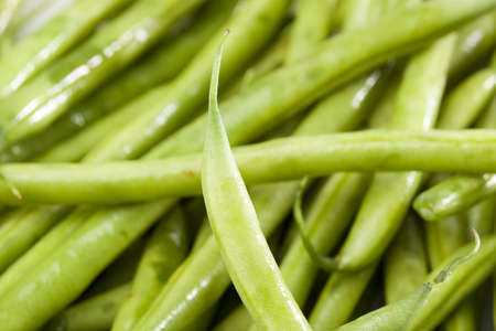 A fresh green string bean against a white background