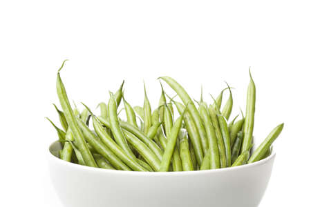 A fresh green string bean against a white background