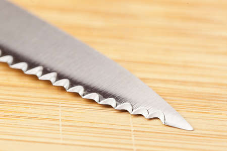 Shiny Metal knife on a wooden cutting board
