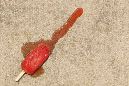 Cold Organic Frozen Strawberry Fruit Popsicle melted on the Groundの写真素材