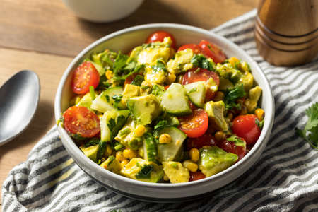 Healthy Organic Avocado Tomato Salad with Herbs and Cucumberの写真素材