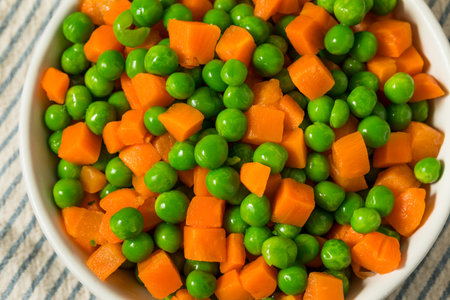 Organic Raw Steamed Frozen Green Peas and Carrots in a Bowlの写真素材