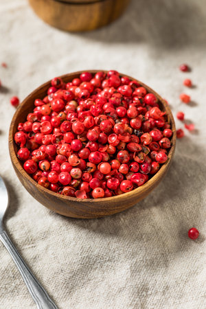 Organic Spicy Red Pink Peppercorns in a Wooden Bowlの写真素材