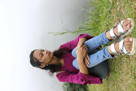 Young woman sitting on the grass and looking up at the sky.の写真素材