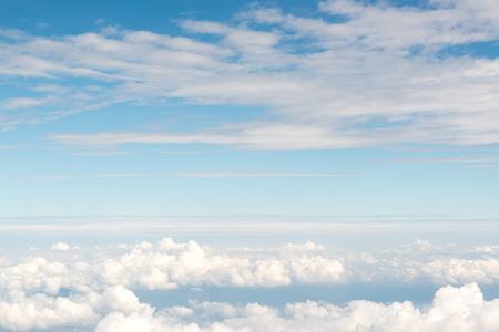 Cloudscape view above white clouds and blue sky from airplane