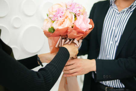 A handsome man is giving flowers to a beautiful girl in the office