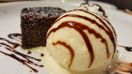 chocolate brownies with ice cream vanilla on a white disk in the restaurantの写真素材