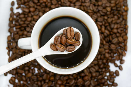 white coffee cup, spoon and roasted coffee beans that isolated on white background. top view.