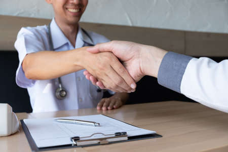 Doctor and a patient man making handshake in the office room, Medical and health care concepts.