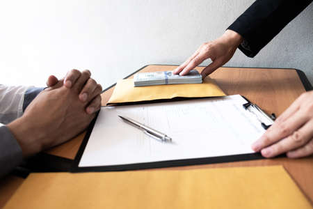 The businessman offered an agreement and a bribe to another businessman in front, Bribery and corruption concept.の写真素材