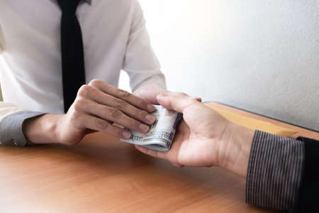 The businessman receiving bribe money from another businessman at the office, Bribery and corruption concept.の写真素材