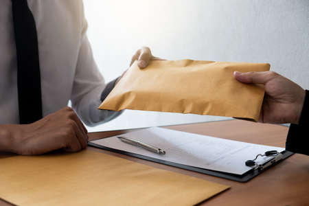 The businessman receiving bribe money in a brown envelope form another man at the office, Bribery...