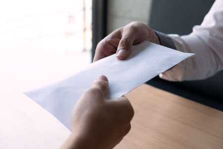 The businessman receiving bribe money in a white envelope form another man at the office, Bribery and corruption concept.の写真素材