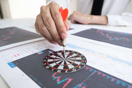 Businessman is holding a darts stick into the bullseye for make targeted of investment, Business and...