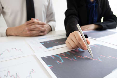 Two business people are discussing and analyze strategy of investment from the stock graph in the...