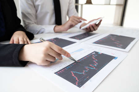 Two business people are discussing and analyze strategy of investment from the stock graph in the office room, Business and finance concept.の写真素材
