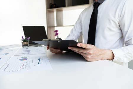 Businessman is analyzing marketing strategy from the selling performance graph in the office room, Finance and accounting concept.の写真素材