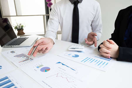 Two business people are discussing and analyze marketing strategy from the sell performance graph in...