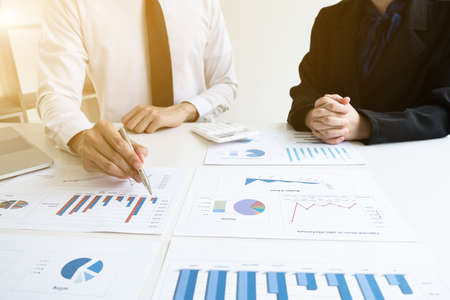 Two business people are discussing and analyze marketing strategy from the sell performance graph in the office room, Finance and accounting concept.の写真素材