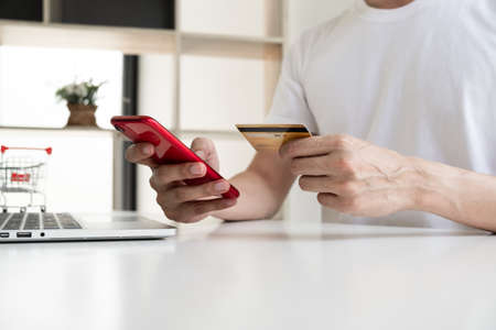 Closeup hand of a men is holding the credit card and using mobile phone for shopping online.の写真素材