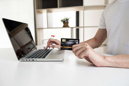 Closeup hand of a men is holding the credit card and using computer notebook for shopping online.  の写真素材