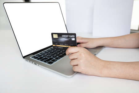 Closeup hand of women is holding a credit card and using computer notebook for shopping online.の写真素材