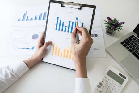 Businessman is analyzing marketing strategy from the selling performance graph in the office room, Finance and accounting concept.の写真素材