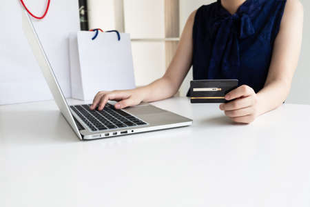 Closeup hand of women is holding a credit card and using computer notebook for shopping online.の写真素材