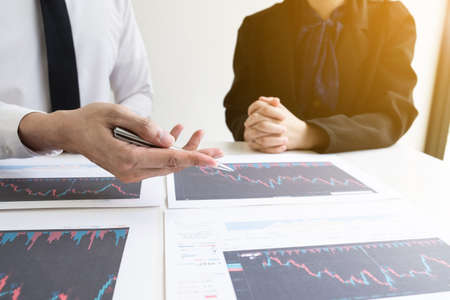 Two business people are discussing and analyze strategy of investment from the stock graph in the office room, Business and finance concept.の写真素材
