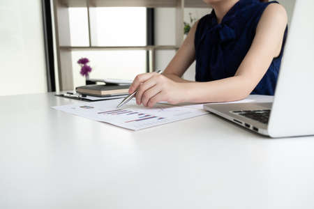 Business women is analyzing marketing strategy from the selling performance graph in the room and work from home, Finance and accounting concept.の写真素材