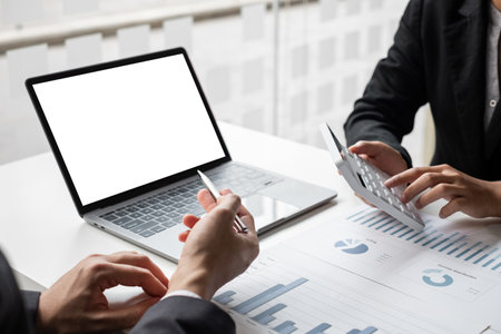 Two businessmen are analyzing earnings on a graph to plan investments in the office room. business discussing and planning strategy concept.の写真素材