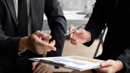Two businessmen are discussing about earnings on a graph to plan investments in the office room. business discussing and planning strategy concept.の写真素材