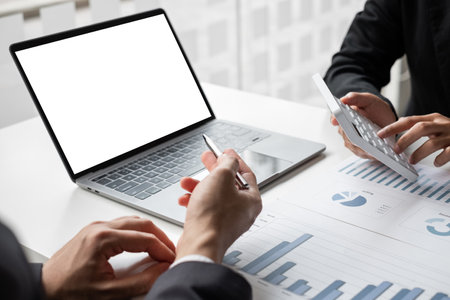 Two businessmen are analyzing earnings on a graph to plan investments in the office room. business discussing and planning strategy concept.の写真素材