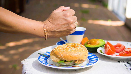 Hands of a woman eating a hamburger at a table outsideの素材