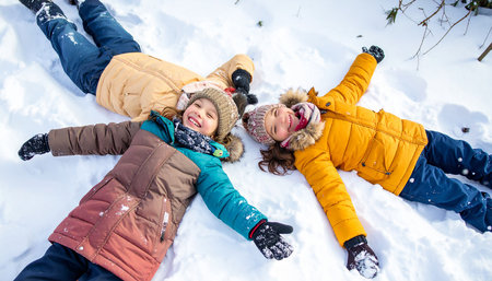 Happy children lying on the snow and having fun in the winter parkの素材
