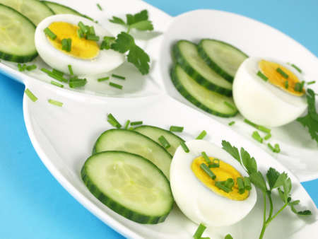 Boiled eggs with chive and cucumber on tasteful plateの写真素材