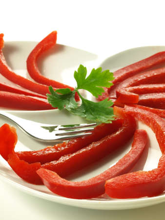 Red bell pepper slices on plate, closeup on isolated background の写真素材