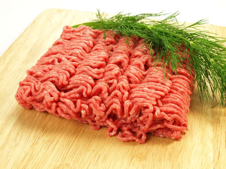 Raw meat with dill on cutting boardの写真素材