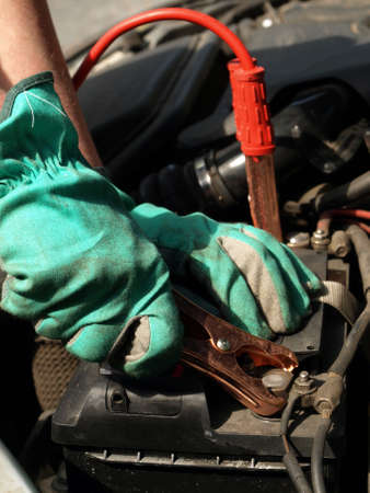 Man hands in gloves recharging battery in car