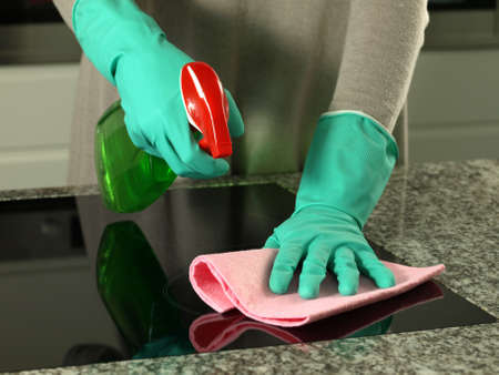 Woman's hands cleaning kitchen top in gloves     