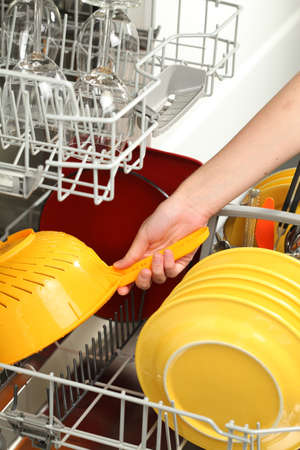 Woman's hand putting dirty dishes into dishwasherの写真素材