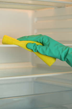 Closeup of woman's hand cleaning a fridge