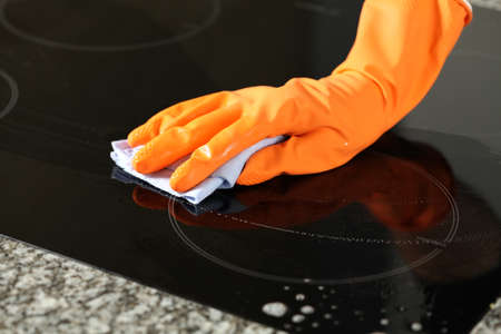 Closeup of hand in glove cleaning a stove