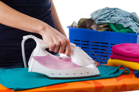 Ironing on ironing board with clothes in a basket の写真素材
