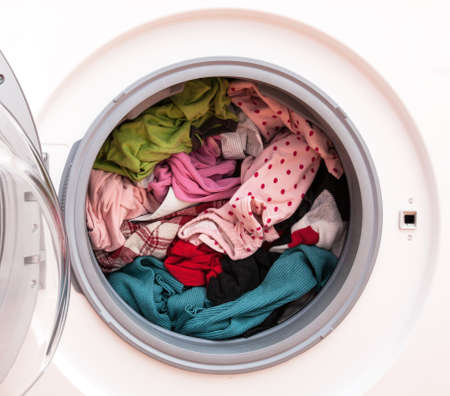 Washing machine full of dirty clothes, closeup