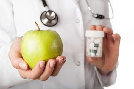 Doctor giving an apple instead of a drugsの写真素材