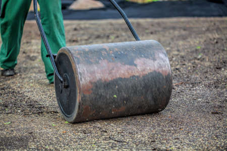 Worker with lawn roller in gardenの写真素材