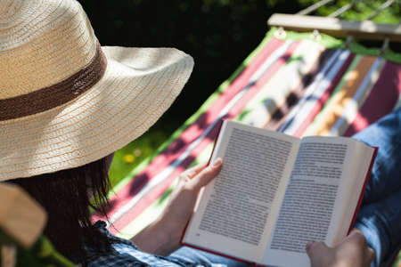 A reading woman relaxing on a hammockの写真素材