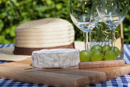 Camembert cheese, a knife and grapes on a boardの写真素材